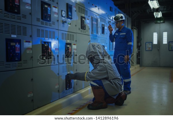 Electrical worker wearing arc\
flash suit protection is used to draw out a large circuit\
breaker.