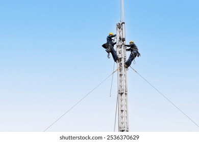 Electrical workers wear safety equipment while climbing a steel tower. Dangerous engineering work. - Powered by Shutterstock