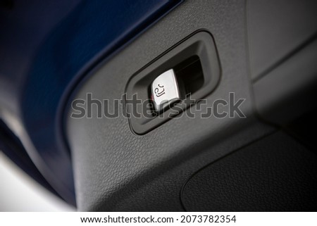Electrically retractable towbar button on trunk door. Close up. Detail. Foldable tow device switch.