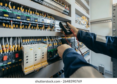 Electrician builder engineer testing and screwing equipment in fuse box and repairing of modern electricity power station using voltmeter. Automatic control cabinet