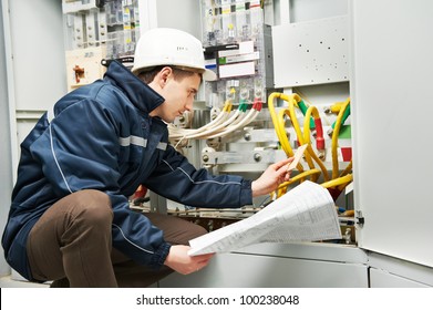 Electrician builder at work inspecting cabling connection of high voltage power electric line in industrial distribution fuseboard