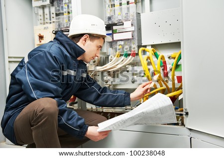 Electrician builder at work inspecting cabling connection of high voltage power electric line in industrial distribution fuseboard