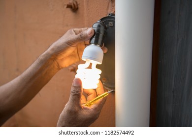 Electrician change light bulb in house exterior wall lamp