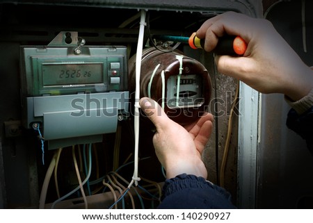 The electrician changes the old electric meter for the new.