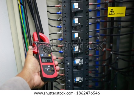 Electrician to check electric current    in cable by ampere clamp meter