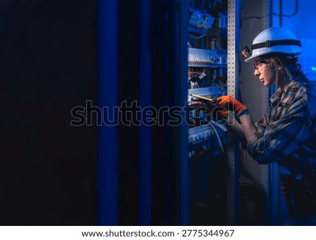 Electrician checking switchboard with voltage tester in server room. Energy infrastructure.