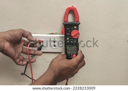 An electrician checking the voltage of a newly installed outlet in the living room with an ammeter tester.