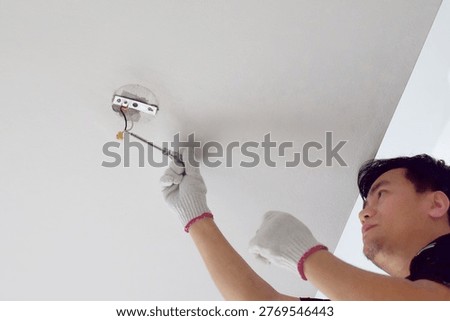 The electrician is disassembling the ceiling light fixture.