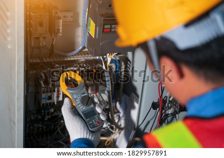 Electrician engineer tester measuring voltage and current of power electric line in electical cabinet control.Electrician use Digital Voltmeter Testing Voltage on automatic control box.Selective focus