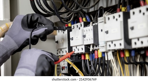 Electrician engineer tests electrical installations and wires on relay protection system. Adjustment of scheme of automation and control of electrical equipment.