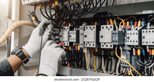 Electrician engineer tests electrical installations and wires on relay protection system.