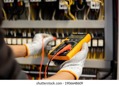 Electrician engineer uses a multimeter to test the electrical installation and power line current in an electrical system control cabinet. - Shutterstock ID 1906648609