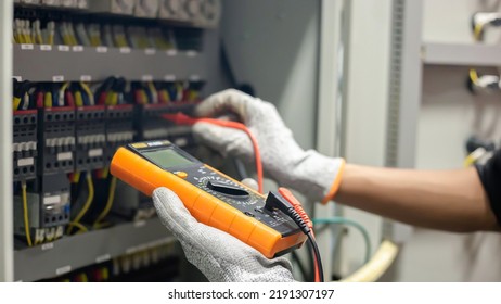 Electrician engineer uses a multimeter to test the electrical installation and power line current in an electrical system control cabinet. - Shutterstock ID 2191307197