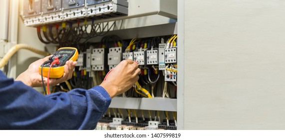 Electrician engineer work  tester measuring  voltage and current of power electric line in electical cabinet control.