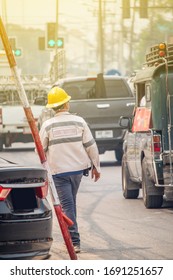 The electrician or engineer working or checking the voltage pillars or poles is walking on the road while working. 