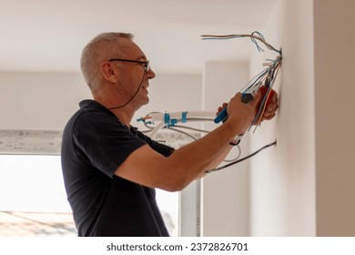 Electrician, examines the cable connection in the electrical line. Technician pull wire from conduit in building site.Builder at work, examines  connecting cables.
