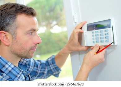 Electrician fitting an intrusion alarm - Shutterstock ID 296467673