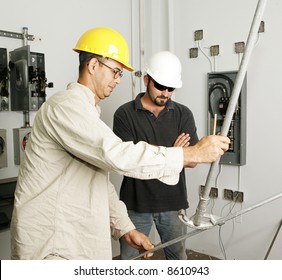 Electrician and foreman bending pipe for a job.  Actual electricians working according to industry safety and code standards.  (markings on bender are instructional not trademarked) - Shutterstock ID 8610943