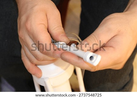 Electrician hands assembling white plastic electrical conduit components for a lamp.