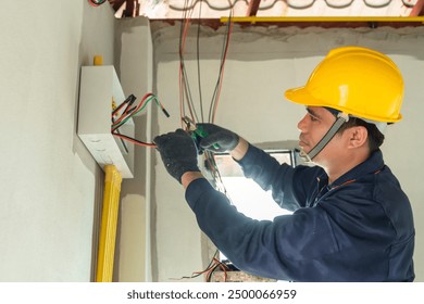 An electrician in a high-visibility vest works on wiring at a construction site. - Powered by Shutterstock