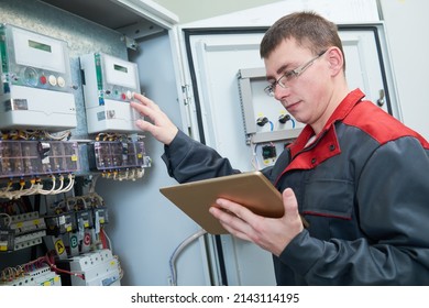 Electrician inspectinf fuse box circuit with tablet computor
