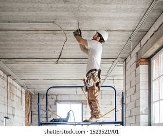 Electrician installer with a tool in his hands, working with cable on the construction site. Repair and handyman concept. House and house reconstruction.