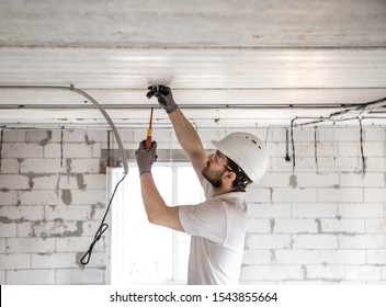 Electrician installer with a tool in his hands, working with cable on the construction site. Repair and handyman concept. House and house reconstruction.
