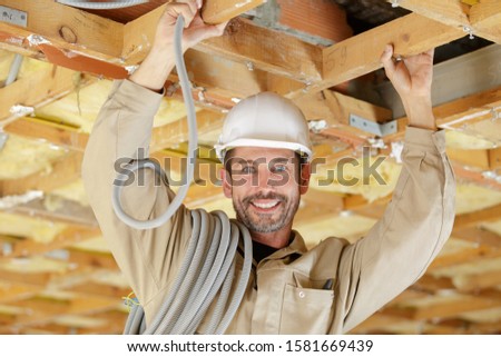 electrician with installing cables into roof space