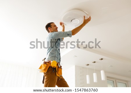 Electrician is installing and connecting a lamp to a ceiling.