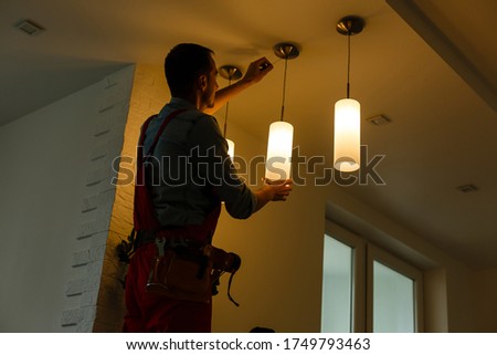 Electrician is installing and connecting a lamp to a ceiling.