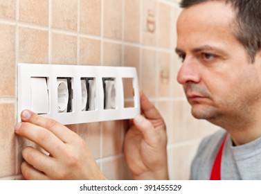 Electrician Installing A Decorative Panel On Electrical Wall Fixture - Closeup, Focus On Frame