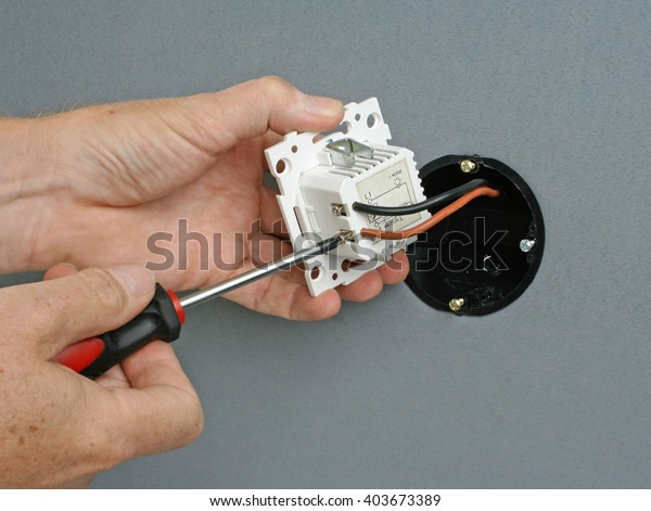 Electrician\
installing a dimmer switch in a wall\
socket