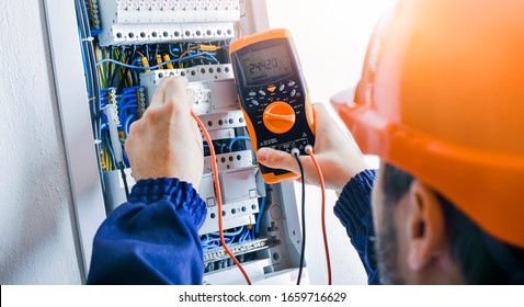 Electrician installing electric cable wires and fuse switch box. Multimeter in hands of electricians detail. - Shutterstock ID 1659716629