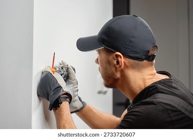 Electrician installing electrical wall switch and connecting wires inside wall using screwdriver. Concept of professional electrical work, home renovation and safe installation.
