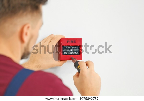 Electrician Installing Fire Alarm System Stock Photo 1075892759