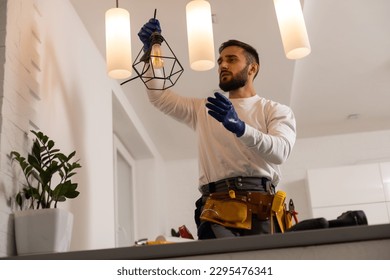 electrician installing led light bulbs in ceiling lamp - Shutterstock ID 2295476341