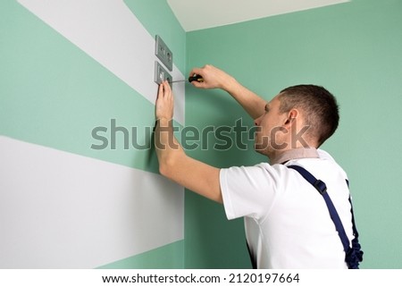 Electrician installing new current socket with screwdriver
