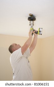 Electrician Installing New Light Fixture And Fan