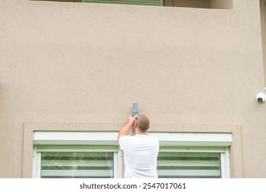 Electrician installing an outdoor wall light fixture on the facade of a residential building - Powered by Shutterstock