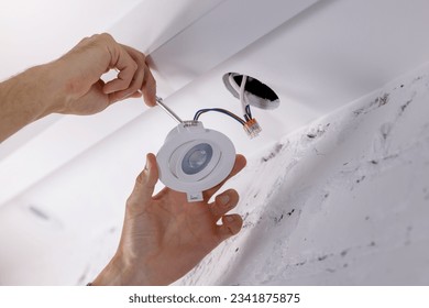 electrician installing recessed lamp in drywall ceiling. led lighting