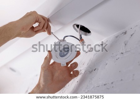 electrician installing recessed lamp in drywall ceiling. led lighting Stockfoto © 