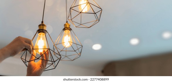 An electrician is installing spotlights on the ceiling. Handyman choosing between energy save and cheap incandescent lamp while changing light in the appartment