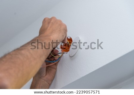 Electrician installs electrical wires and socket on house - closeup
