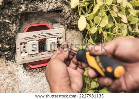 An electrician installs a new combo switch and outlet to an outdoor wall. A handyman doing electrical home repair.