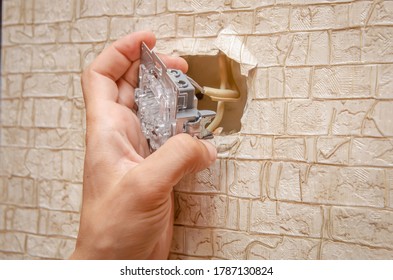 Electrician installs a switch on the wall with a screwdriver close up