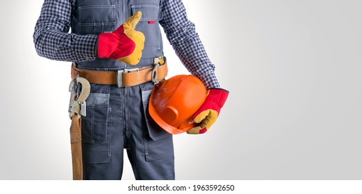 Electrician In Jumpsuit Holding Helmet, Showing Thumb Up Recommend Approve Sign Over Grey Background. Banner.