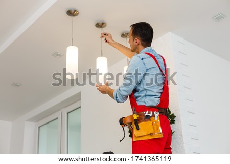 Electrician man worker installing ceiling lamp