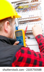 The electrician measures the electric current on the wires and the fuse switch. Multimeter in the hand of electricians detail. - Shutterstock ID 2105750588