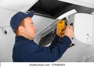 Electrician Measuring Voltage Of Air Conditioner In Office