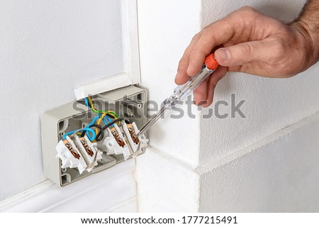 Electrician with neon-lamp tester checking voltage indoors, closeup 